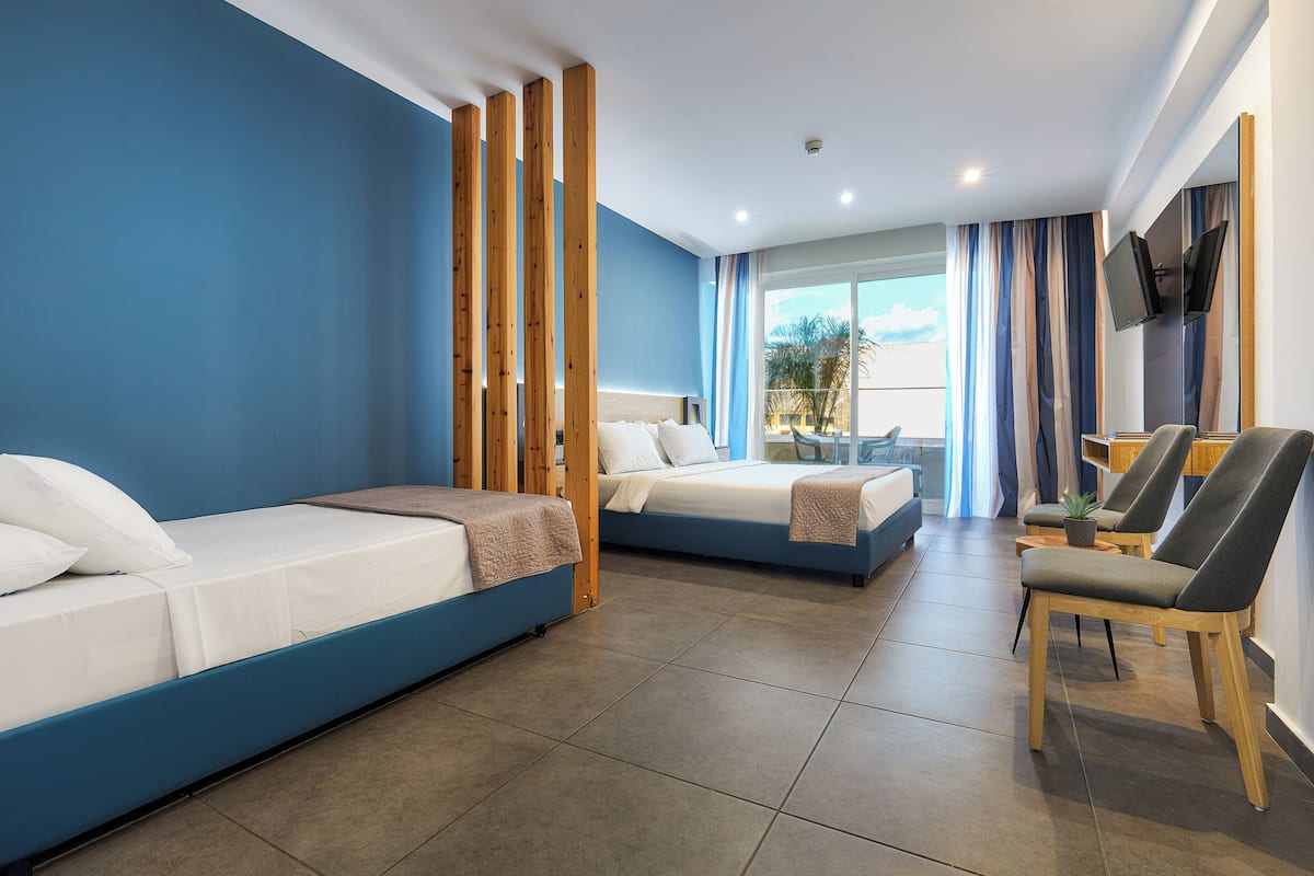 Ein Hotelzimmer mit zwei Betten, einem Fernseher, einem Schreibtisch und einem Stuhl.