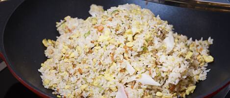 Un wok rempli de riz frit contenant des œufs et des légumes.