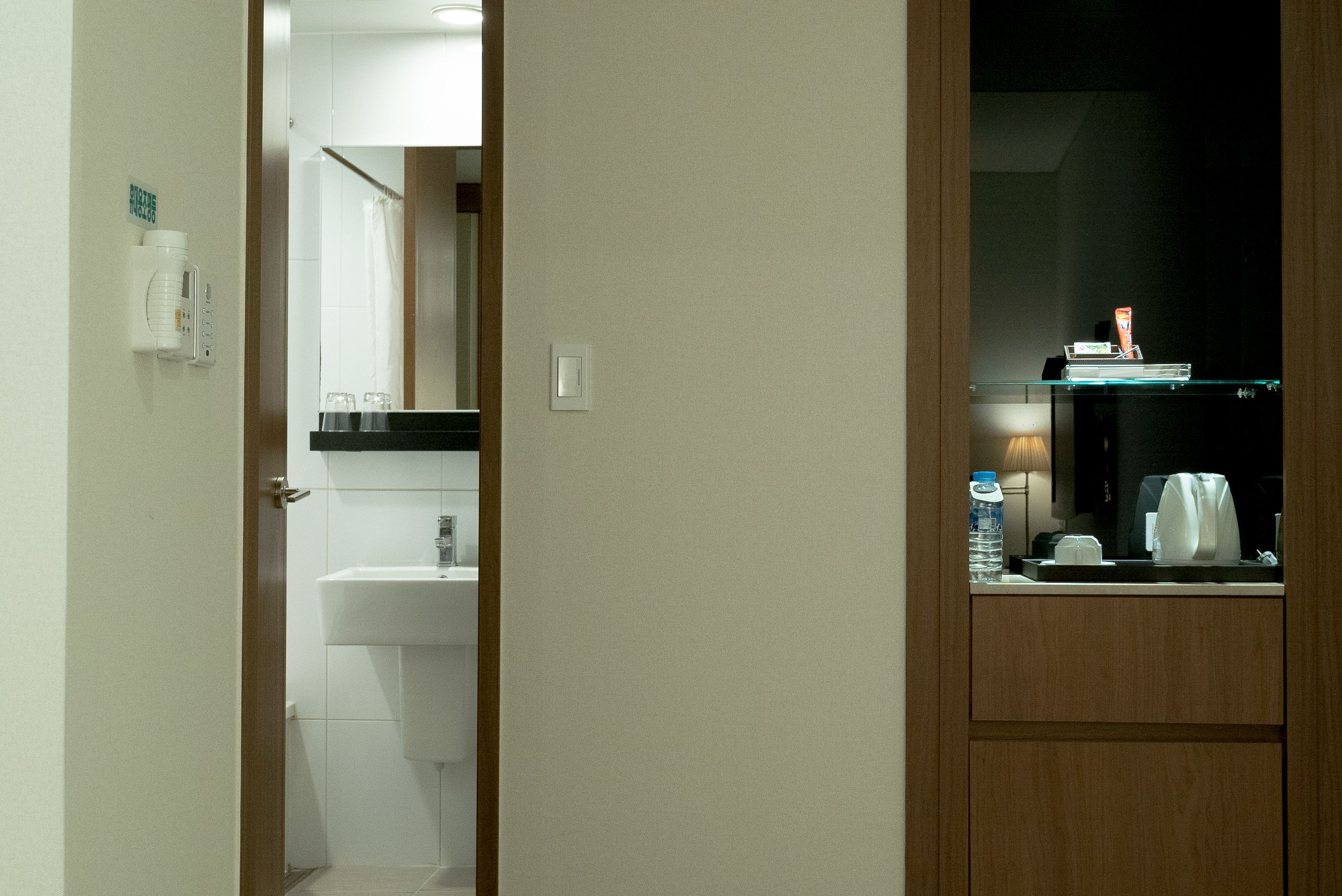 Et badeværelse på et hotel med håndvask, spejl og en lille hylde med toiletartikler.