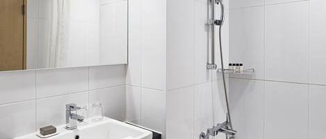 A modern bathroom with a white sink, mirror, and bathtub.