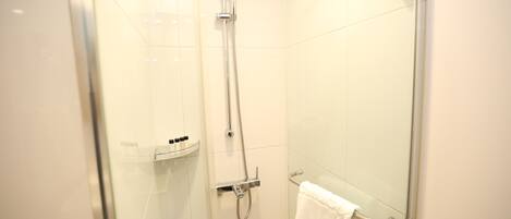 Une douche en verre avec un pommeau de douche amovible et un porte-serviettes.