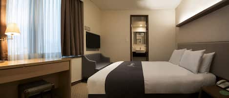 Een hotelkamer met een bed, nachtkastje, lamp, stoel en een televisie.