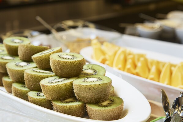 A buffet with sliced kiwi and pineapple arranged on white plates. - Hotel Venue G (Seoul)