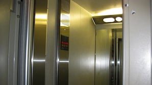 Hissin sisätilat: metalliset seinät, painikkeilla varustettu ohjauspaneeli ja digitaalinen näyttö.