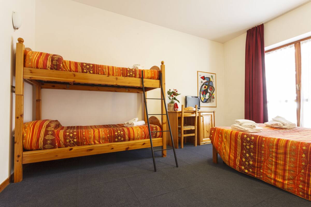 A room with a bunk bed, a desk, and a chair.