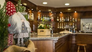 A bar area with wooden cabinets, a counter, and a stool. - Club Hotel Solaris (Cesana Torinese)