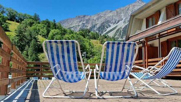 Two blue and white striped lounge chairs on a brick patio with a mountain view. - Club Hotel Solaris (Cesana Torinese)