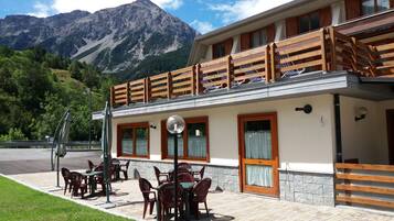 Un restaurante con terraza, barandillas de madera y vistas a la montaña.