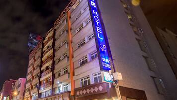 A multi-story hotel with a prominent neon sign, large windows, and a visible entrance.