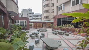 A courtyard with potted plants, stone seating, and a tiled floor. - KKS Hotel (Hualien City)