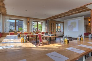 A conference room with long tables, chairs, and a projector screen.