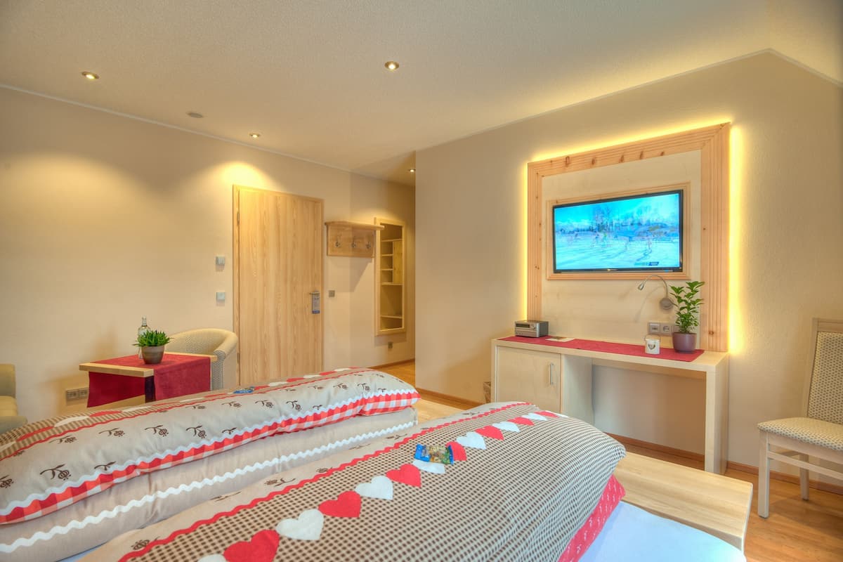A hotel room with a bed, a desk, a TV, and a wardrobe.
