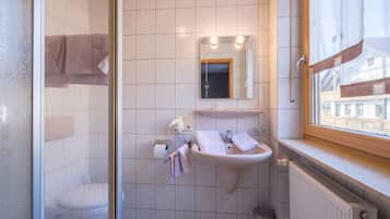 Un baño con ducha, lavamanos y ventana.