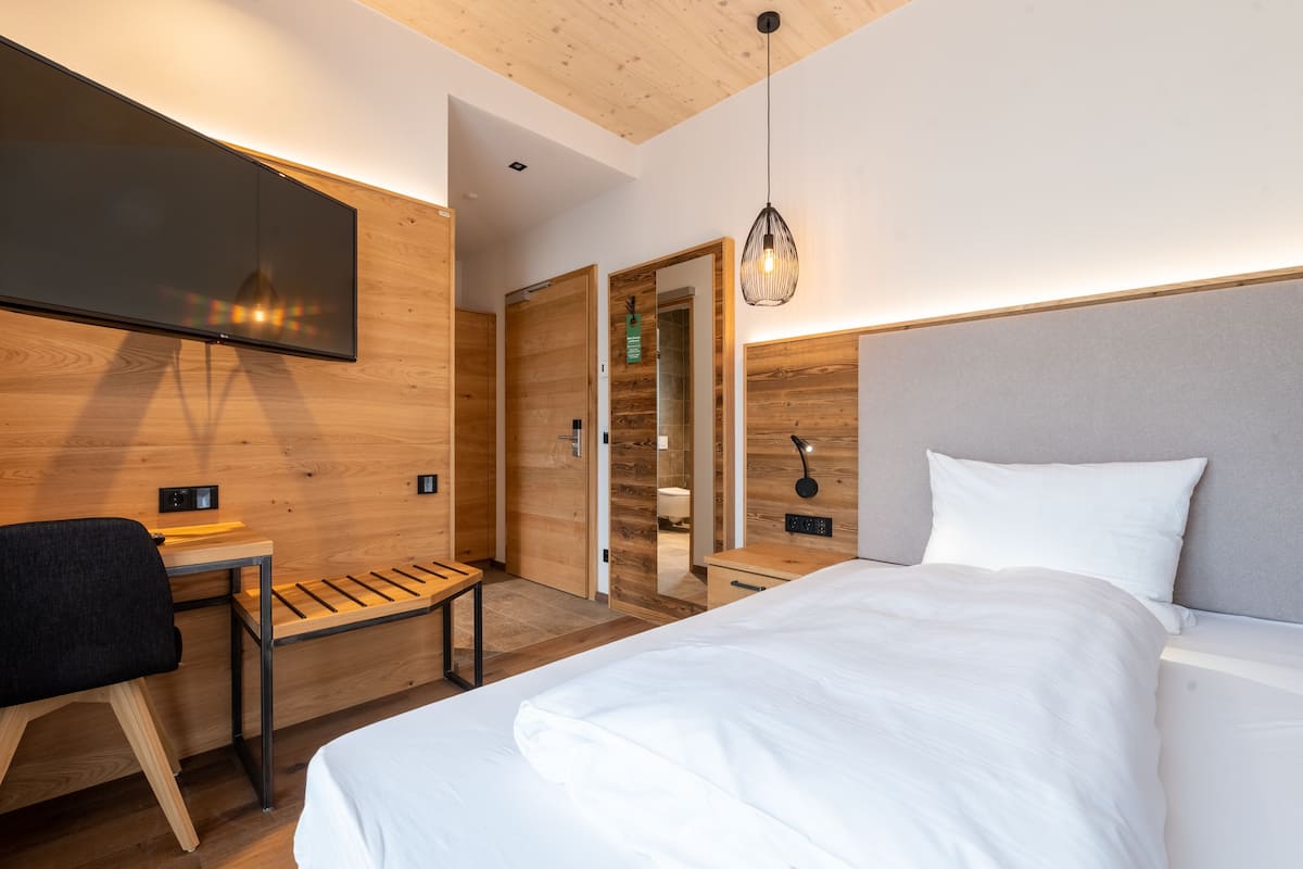 A modern hotel room with a large bed, a desk, and a television mounted on the wall.
