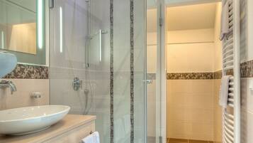 Een moderne badkamer met een douche met glazen wand, een wastafel met spiegel en een handdoekrek.