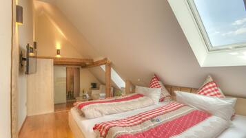 Ein Schlafzimmer mit schrägverdeckter Decke, einem Oberlicht und einem Bett mit roter und weißer Bettwäsche.