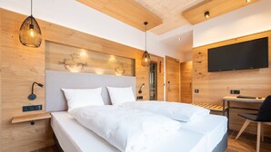 A modern hotel room with a large bed, wooden headboard, bedside tables, a desk, and a flat-screen TV. - Landhotel Goldenes Kreuz (Moosbach)