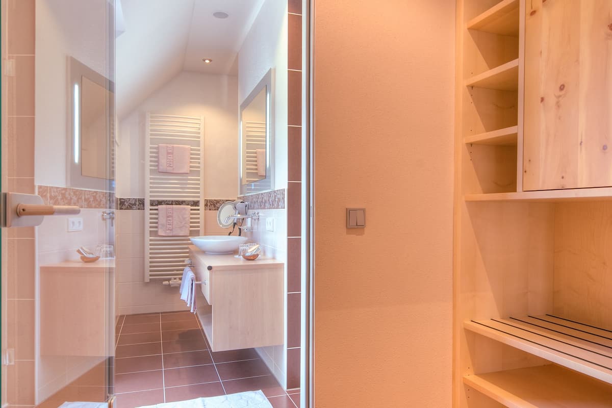 A modern bathroom with a glass shower enclosure, a wooden vanity, and a built-in shelf unit.