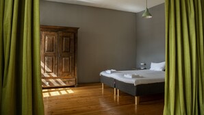 A bedroom with a wooden wardrobe, a bed with white linens, and a hanging light fixture. - Bookinn B&B (Vilnius)