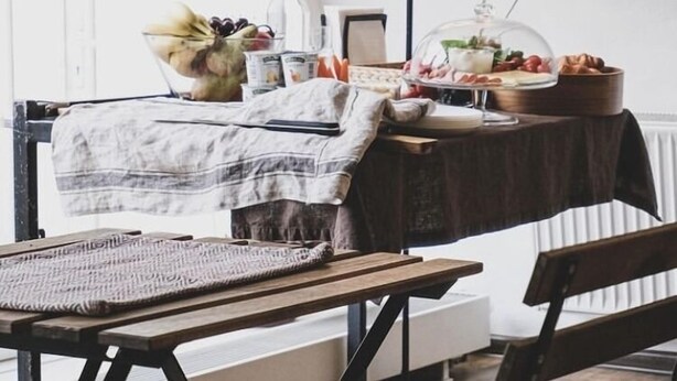 A cozy dining area with a table set for a meal, a lamp, and a bowl of fruit. - Bookinn B&B (Vilnius)