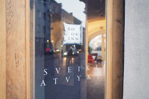 Una ventana con el texto "BOOK INN" y "SVEIKATVYK", indicando el nombre del establecimiento.