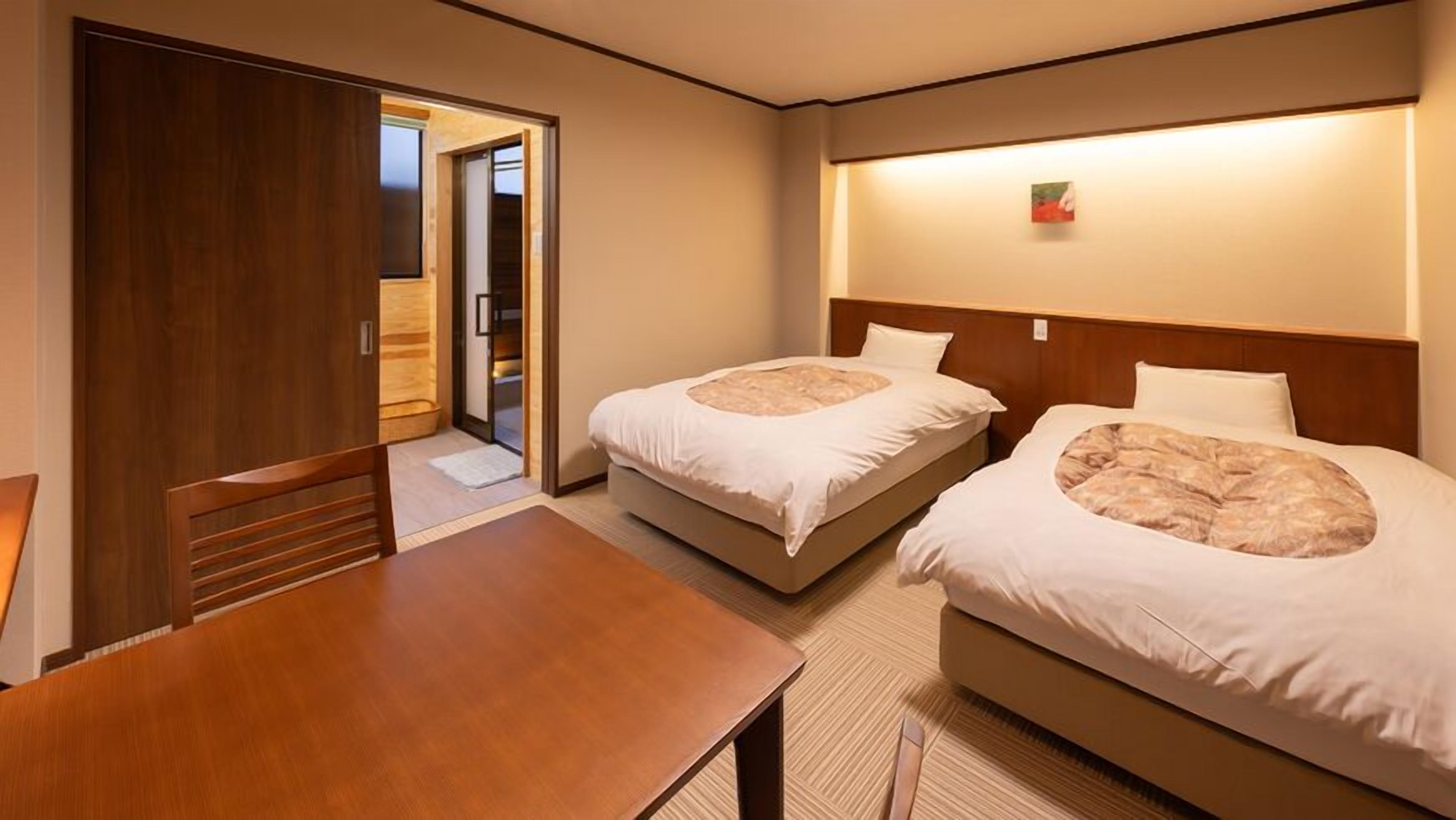 Een hotelkamer met twee bedden, een houten tafel en een kledingkast.