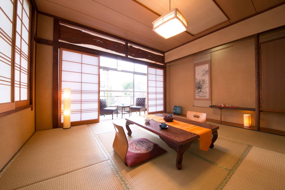 Una habitación japonesa tradicional con suelo de tatami, una mesa baja y puertas correderas.