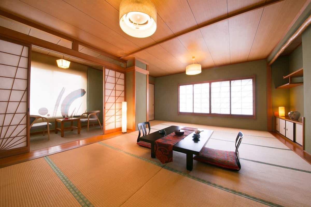 Een traditionele Japanse kamer met tatami vloeren, een lage tafel met een rode mat en schuifdeuren.