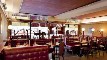 Un restaurante con cabinas y mesas, ventanas amplias y techo de madera.