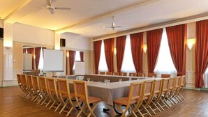 A conference room with a long table, chairs, a whiteboard, and curtains.