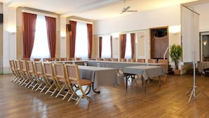 A conference room with long tables, chairs, and ceiling fans.