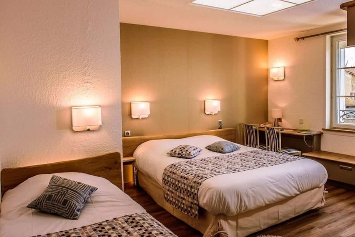 Une chambre d’hôtel avec deux lits, un bureau et une chaise.