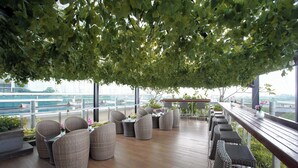 A rooftop terrace with wicker furniture, a wooden deck, and a view of the cityscape. - Vasaka Hotel Jakarta managed by DAFAM (Jakarta)
