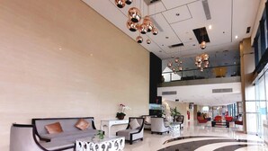 A spacious lobby with a modern design, featuring a seating area with sofas and armchairs, a reception desk, and a large, curved black and white floor design. - Vasaka Hotel Jakarta managed by DAFAM (Jakarta)