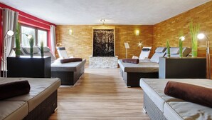 Une salle de spa équipée de deux tables de massage, d’un mur en pierre et d’un plancher en bois.