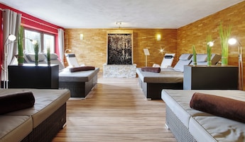 A spa room with two massage tables, a stone wall, and a wooden floor.