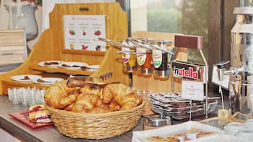 A breakfast buffet with croissants, Nutella, and other spreads.