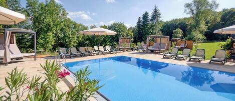 Una piscina techada, una piscina al aire libre, sombrillas