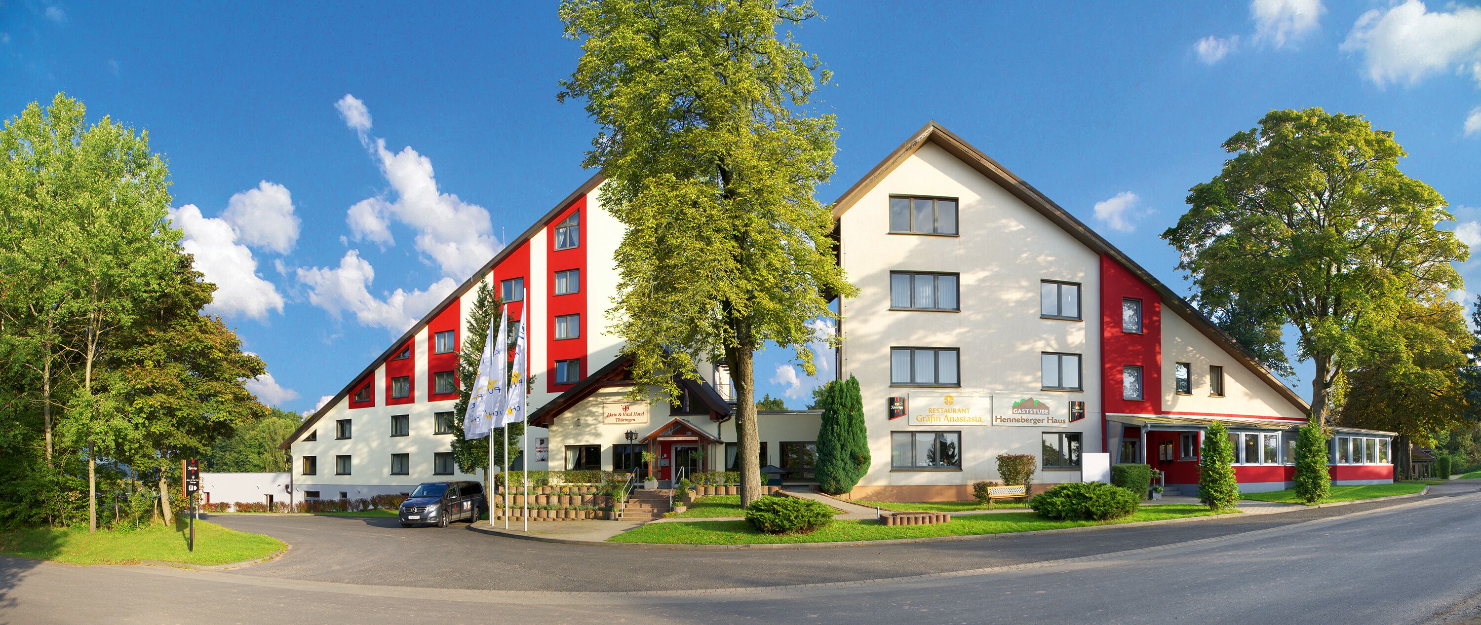 A hotel with a red and white facade, multiple windows, and a visible restaurant named "Restaurant Grafit Anstasia."