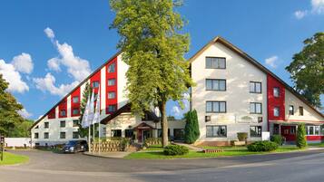 A hotel with a red and white facade, multiple windows, and a visible restaurant named "Restaurant Grafit Anstasia."