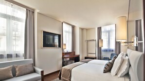 Une chambre d’hôtel comprenant un lit, un canapé, un bureau, une télévision et une salle de bain.