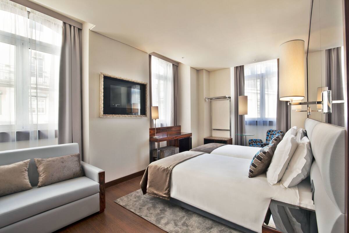Una habitación de hotel con cama, sofá, escritorio, televisor y baño.