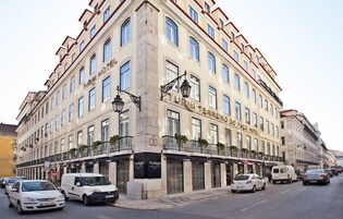 Un edificio ad angolo con diversi piani, una segnaletica ben visibile per "Turim Hotel" e diverse auto parcheggiate lungo la strada.