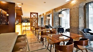 Un restaurant moderne avec des tables et des chaises en bois, un bar et de grandes fenêtres dotées de rideaux.