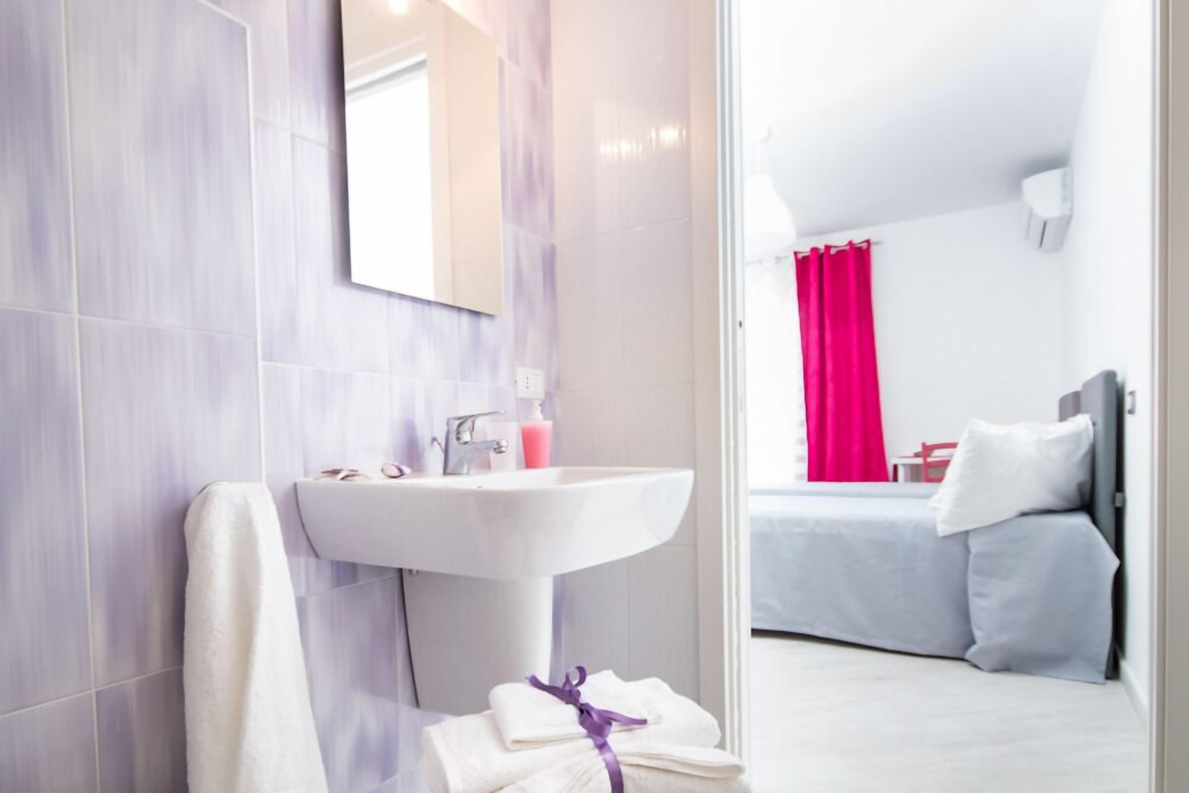 Un baño moderno con lavamanos blanco, espejo y toallero.