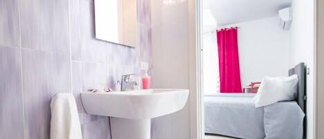 Un baño moderno con lavamanos blanco, espejo y toallero.