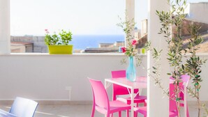 A bright room with a white table and pink chairs, a yellow plant, and a vase with flowers.
