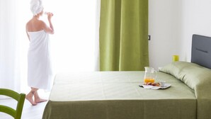 A room with a bed, a table with breakfast items, and a green curtain.