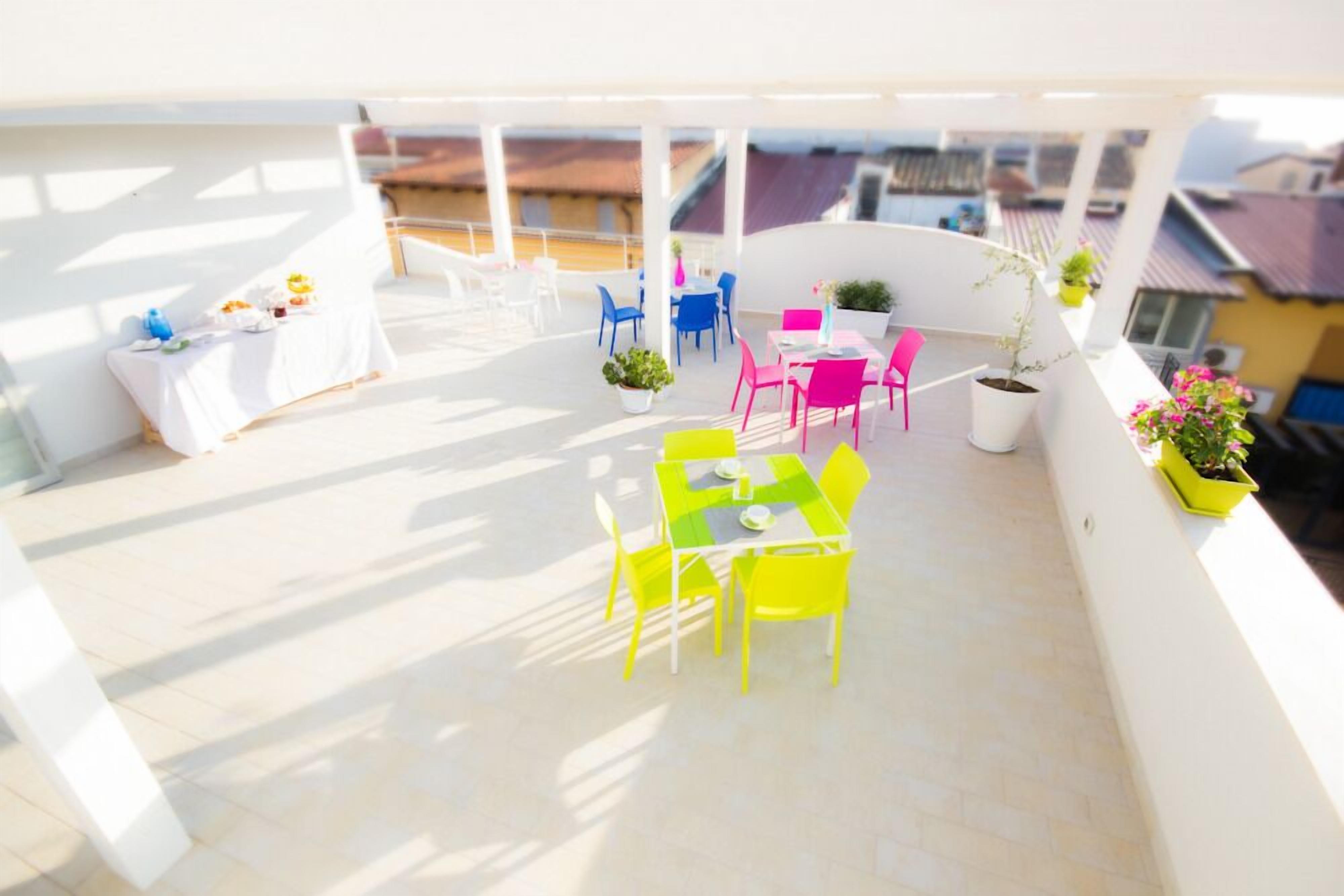 Une terrasse sur le toit, avec une table et des chaises, des plantes en pot et une vue sur les bâtiments.