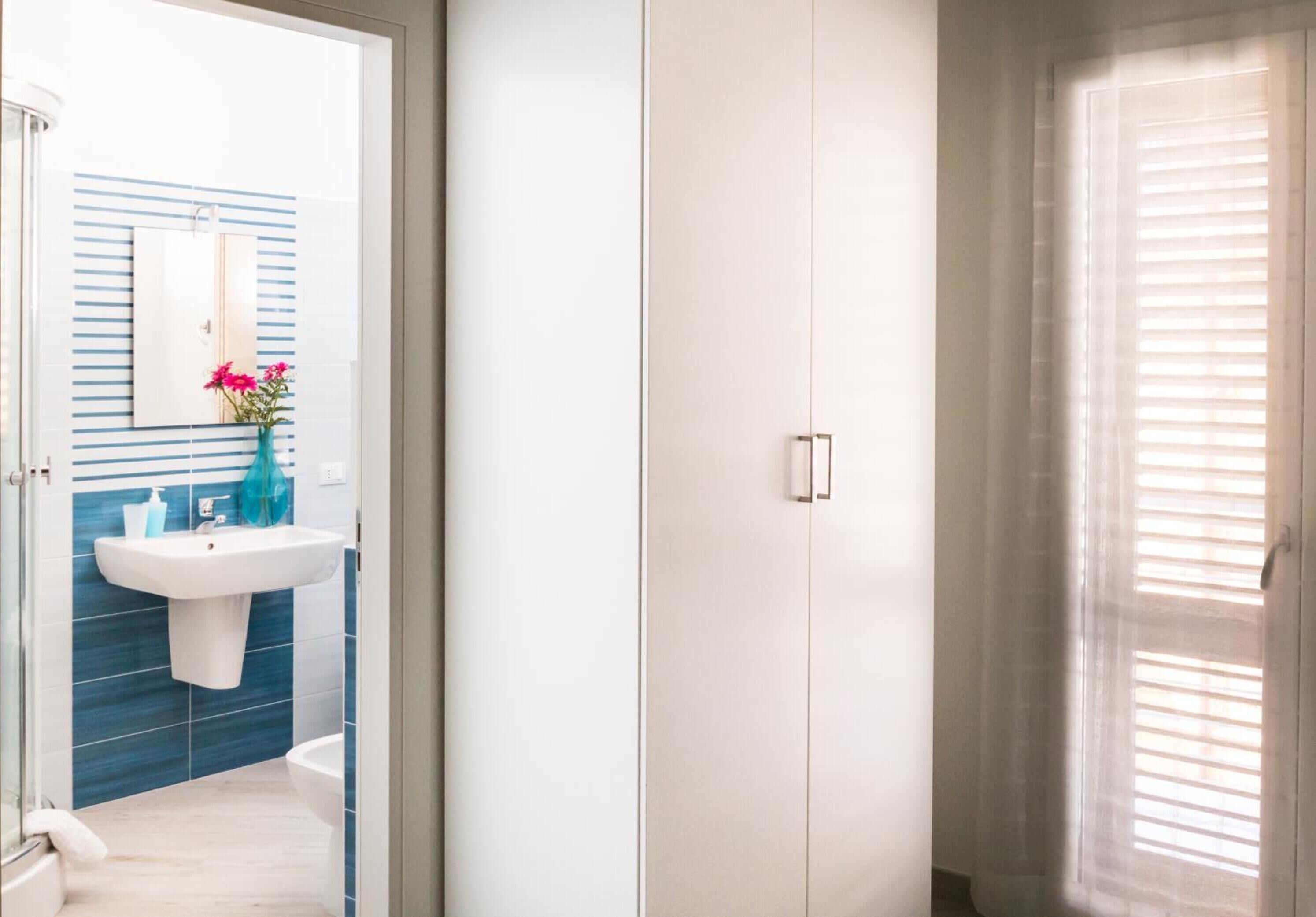 A bathroom with a sink, mirror, and blue-striped wall tiles.